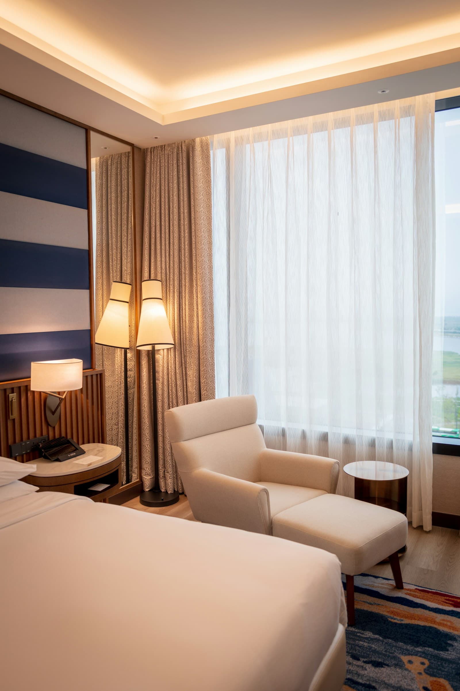 Bright elegant hotel room with a calm armchair and sheer curtains