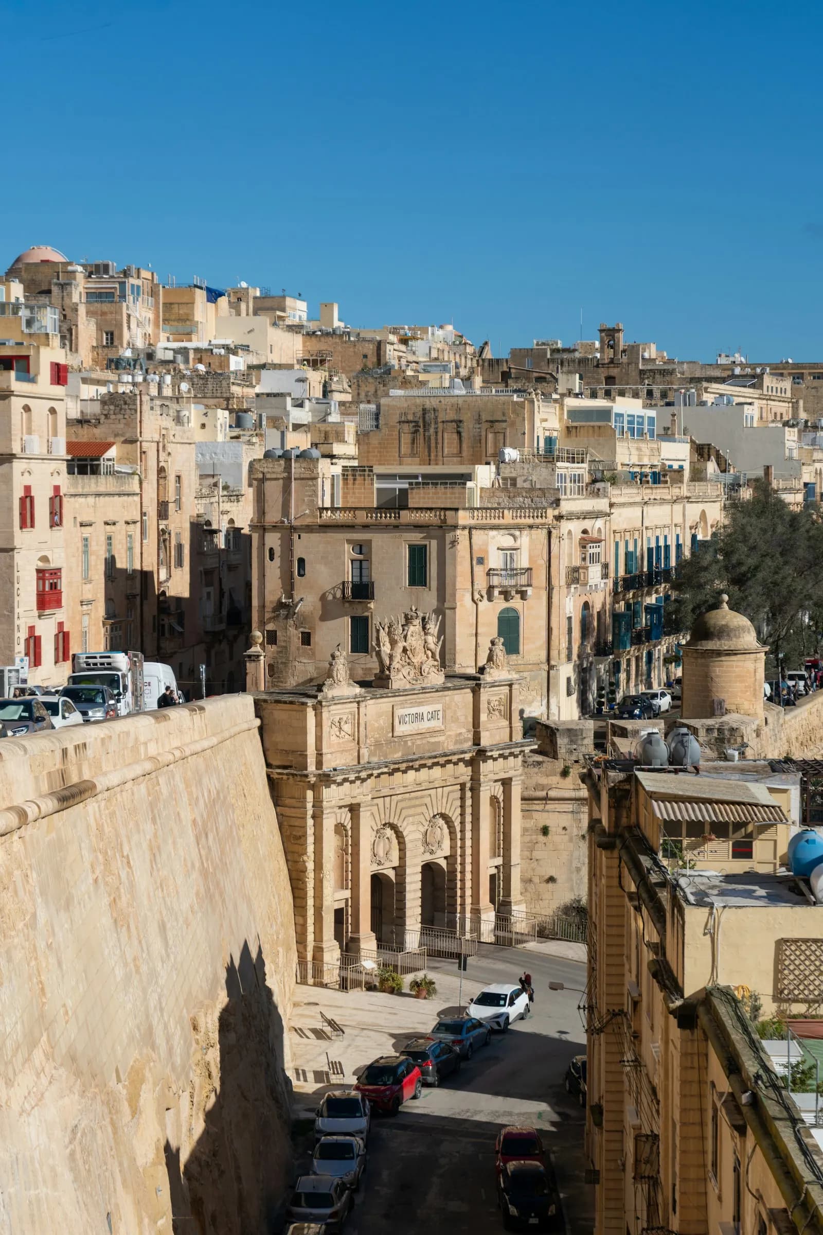 An ornate historic gate and limestone buildings in Valletta, Malta